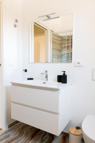a white bathroom with a sink and a mirror at Sahil Apartment in Giulianova
