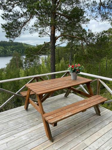 a wooden picnic table with a pot of flowers on a deck at Traditional 60S Cabin By Langåsdammen Lake in Levanger