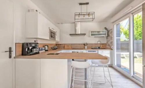 eine Küche mit weißen Schränken und einer Theke mit Stühlen in der Unterkunft Family House Near Mousterlin Beaches in Fouesnant