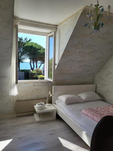 une chambre avec un lit et une grande fenêtre dans l'établissement Maison de KERLEVEN PLAGE, à La Forêt-Fouesnant