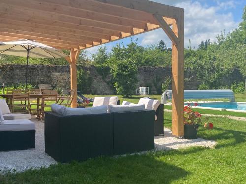 a patio with couches and an umbrella and a pool at Chez Odette chambre Erable et Glycine in Esnoms-au-Val