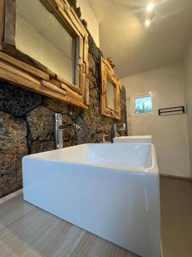 a white sink in a bathroom with a stone wall at Vitamin Sea Guesthouse in Lajares