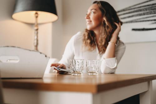 a woman sitting at a desk with a laptop and glasses at Boutique Hotel Villa Monika in Westerland (Sylt)