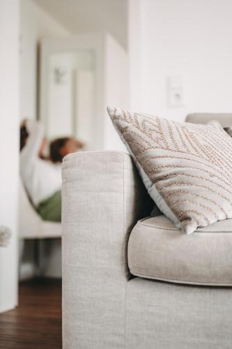 a couch with a pillow and a person laying on a bed at Boutique Hotel Villa Monika in Westerland (Sylt)