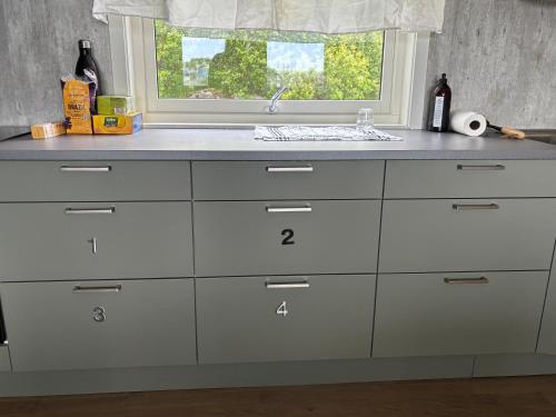 a kitchen counter with white cabinets and a window at The Angler's House in Ballstad