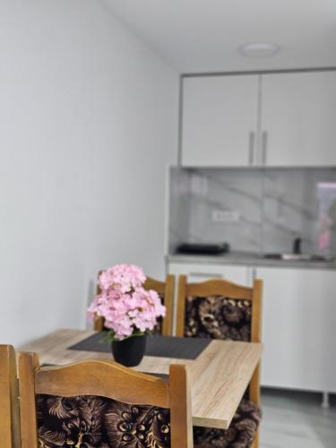 a dining room table with a vase of flowers on it at Studio Dana in Arandjelovac