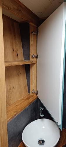 a bathroom with a white sink and wooden cabinets at Tiny House Dreiländereck in Neu-Moresnet