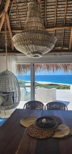 a dining room with a table with a view of the ocean at Mar-Me-Quer, Eco Beach Retreat in Inhambane