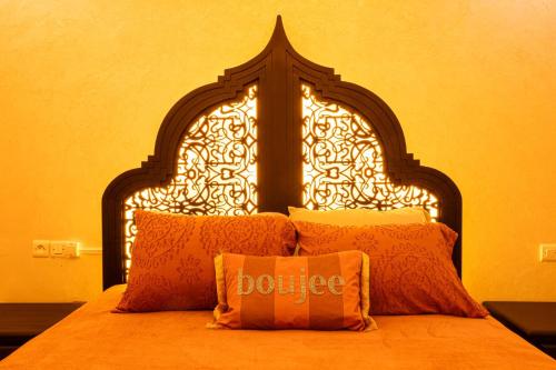 a bed with an ornate headboard with an orange bedspread at HAGS Apartment - Traditional Modern Apartment, full AC, 10m from airport in Marrakech