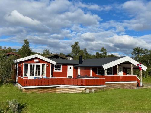 a red and white house with a green lawn at Øse Camping in Gratangen