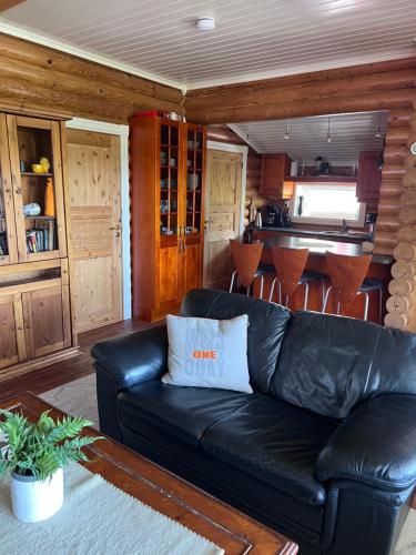 a living room with a black leather couch and a kitchen at Øse Camping in Gratangen