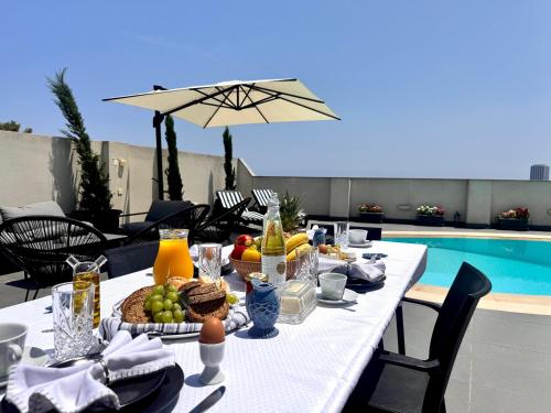a table with food and drinks next to a pool at St Julians Hillside villa with Pool in Is-Swieqi