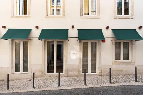 a facade of a building with green awnings on it at Casa Teva Lisboa Boutique Hotel by chic&basic in Lisbon