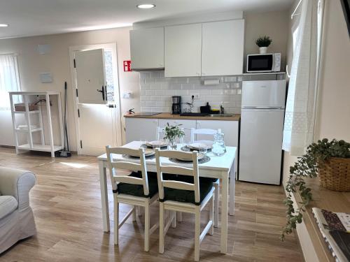 a kitchen with a white table and a white refrigerator at As Cortiñas, casa vacacional completa en Laxe 