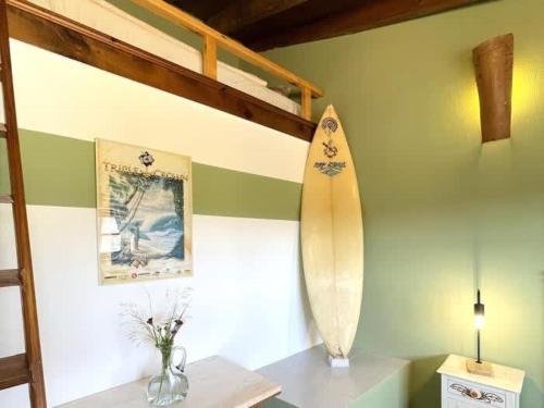 Una tabla de surf en una pared junto a una mesa con una lámpara. en Da Silva Surfcamp- 3 Bettzimmer mit Frühstück, en Lourinhã