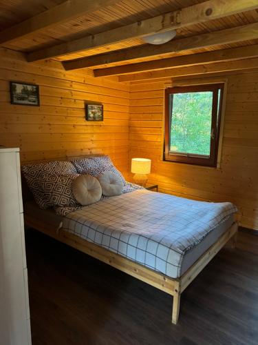 a bed in a log cabin with a window at Domki nad morzem - Wisełka in Wisełka