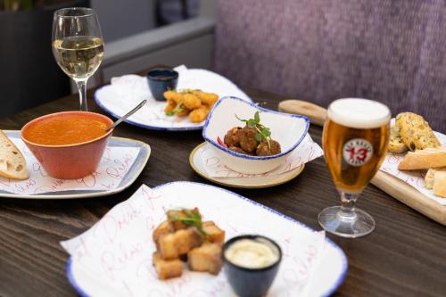 a table with plates of food and two glasses of beer at Leonardo Hotel Cork in Cork