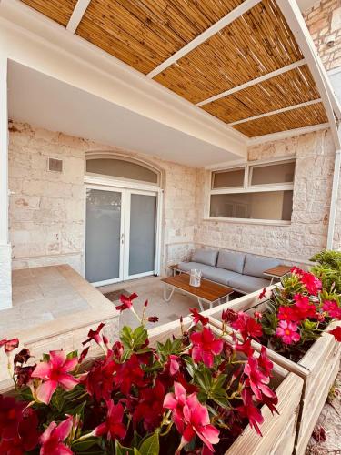 a patio with red flowers and a couch at Agape B&B Monopoli in Monopoli