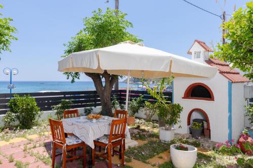 a table with a white umbrella and a dog house at Stegnailion in Archangelos