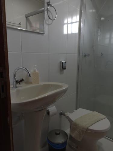 a white bathroom with a sink and a toilet at Chalé Topázio in Monte Verde