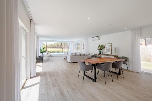 a living room with a table and chairs and a couch at Aroeira Modern Grand Villa With Pool by Homing in Aroeira