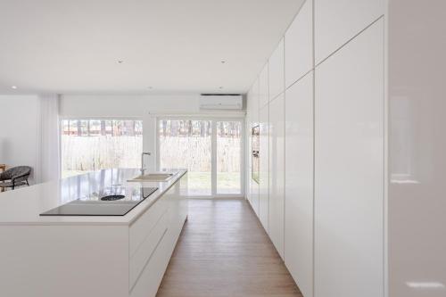 una cucina bianca con un lavello e un bancone di Aroeira Modern Grand Villa With Pool by Homing a Aroeira