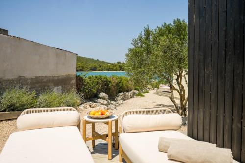 2 sillas y una mesa con un bol de fruta en el patio en TheBeachVilla 3, en Tisno