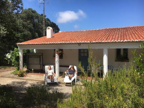 two people sitting in lawn chairs in front of a house at Arneiro de Valverde - Nature & Magical Sunset in Odemira