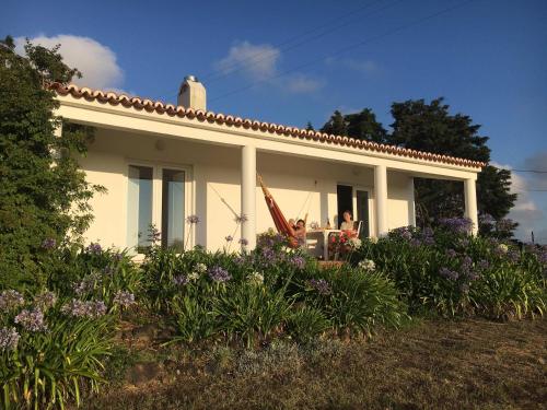 a white house with two people sitting at a table at Arneiro de Valverde - Nature & Magical Sunset in Odemira