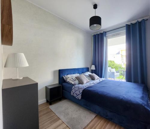 a bedroom with a blue bed and a window at Apartament Sand&Blue z basenem in Sztutowo