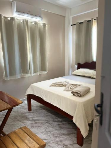 um quarto com uma cama com lençóis brancos e janelas em Hotel Beira Rio em Oiapoque