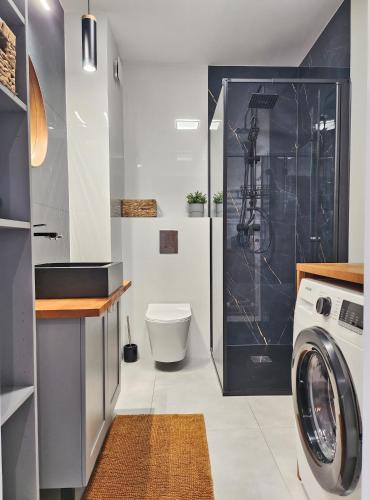 a bathroom with a toilet and a washer and dryer at Apartament Sand&Blue z basenem in Sztutowo