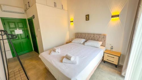 a bedroom with a white bed and a green door at Carnaby Butik Otel Küçükköy in Ayvalık