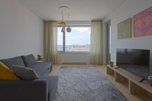 a living room with a couch and a large window at SKAU Sky Park Green by Zaha Hadid 22 floor 1 Tower Panoramic View Free Parking in Bratislava