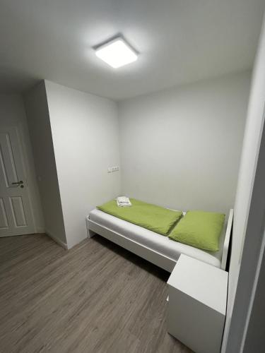 a small room with a bed with a green blanket at Appartementhaus Brunsholm in Esgrus