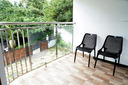 two black chairs sitting on a balcony with a view at Enhance Lifestyle Service Apartments in Thamarassery