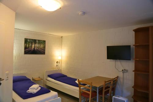 a room with two beds and a table and a television at Monteurzimmer an der Schlei in Rabenkirchen-Faulück
