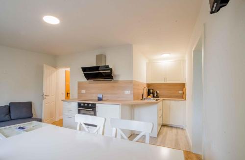 a small kitchen with white cabinets and white chairs at Appartementhaus Schleiblick in Kappeln