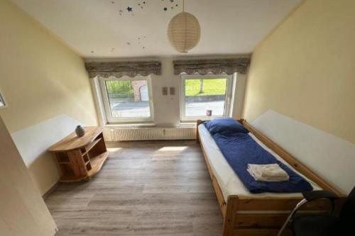 a bedroom with a bed and a table and two windows at Monteurzimmer an der Schlei in Rabenkirchen-Faulück