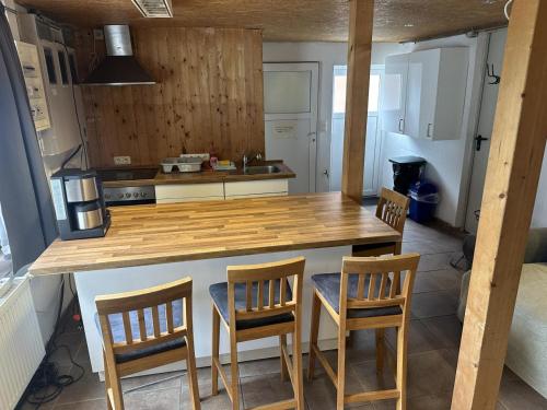 a kitchen with a wooden counter and four chairs at Monteurzimmer an der Schlei in Rabenkirchen-Faulück
