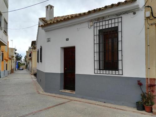 a white building with a red door on a street at La Vila in Villajoyosa