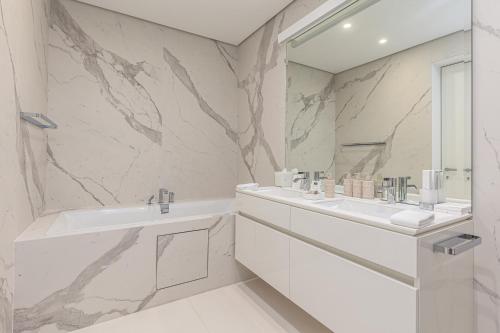 a white bathroom with two sinks and a mirror at Dukley Hotel & Resort in Budva