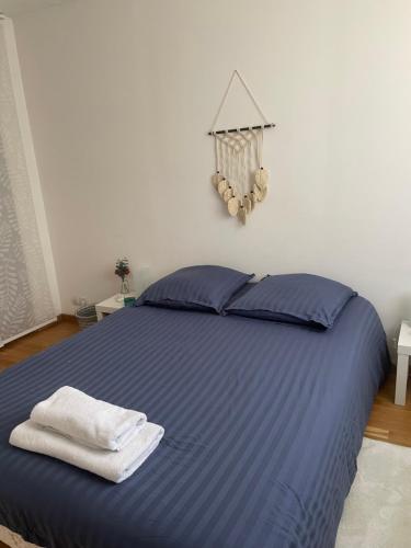 a bedroom with a blue bed with towels on it at Maison entre culture et détente in La Celle-Saint-Cloud