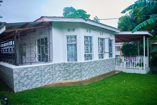 a small white house with a porch and green grass at Villa Malkia's in Enaboishu