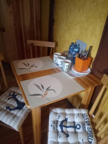 a table with two chairs and a table with cups on it at Dom Gościnny Matysowka in Jarosławiec