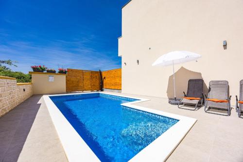 a swimming pool with two chairs and an umbrella at Holiday Home Mario in Pula