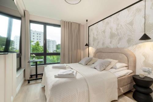 ein Schlafzimmer mit einem weißen Bett mit einem großen Fenster in der Unterkunft Luxury Apartment with Parking and Air Conditioning in Sopot by Renters Prestige in Sopot