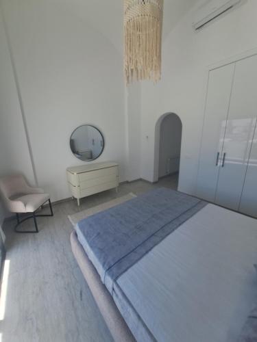 a white bedroom with a large bed and a chair at Villa julia in Hammamet