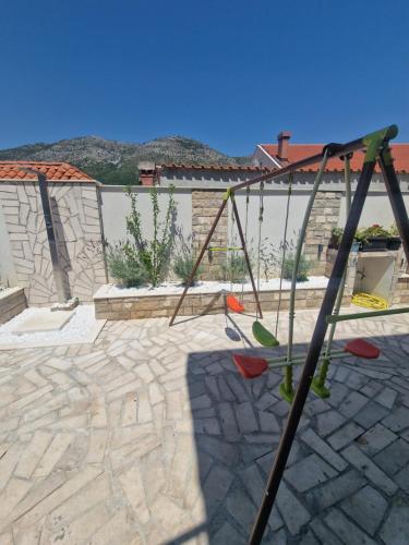 a swing set in a backyard with a stone patio at Apartment Casa Lumina - 5 minutes to the airport and centar all private in Zvekovica