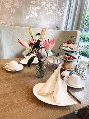 a wooden table with plates of food and flowers on it at Fichtenwald-Ihr Boutique I Glück`s Hotel in Bad Füssing